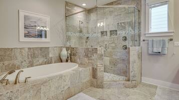 Une salle de bain moderne avec une douche à parois de verre, une baignoire sur pieds et un grand tableau encadré au mur.