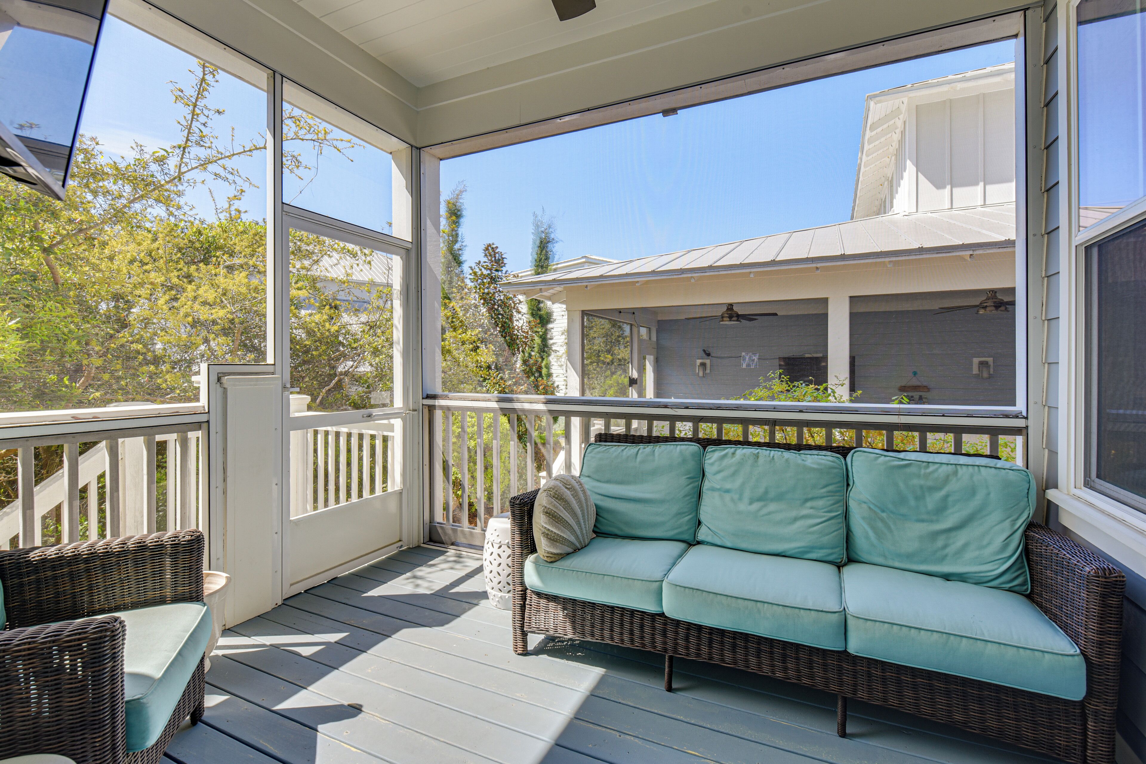A covered porch with a wicker sofa and a wicker chair.