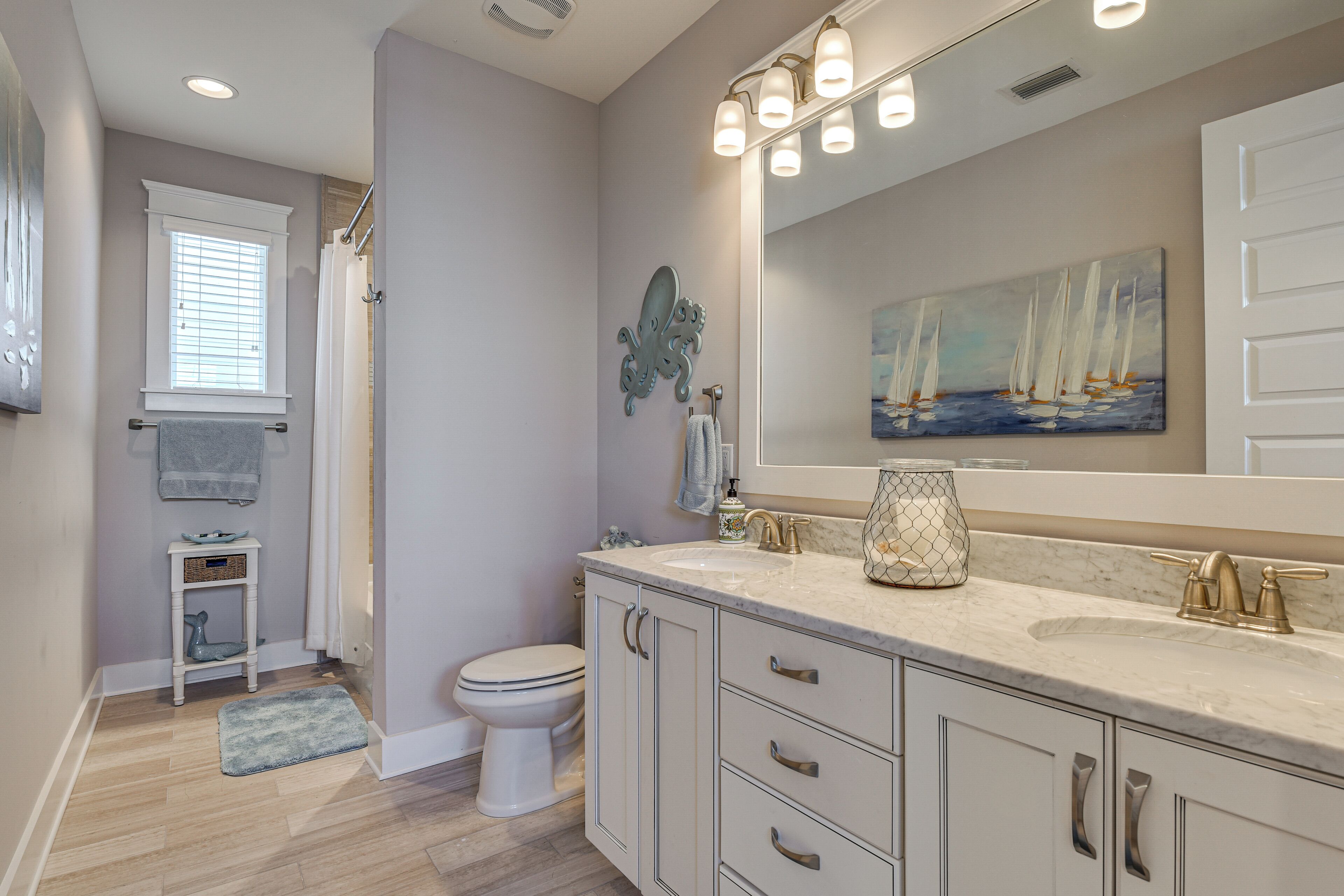A bathroom with a toilet, sink, vanity, and a large mirror.