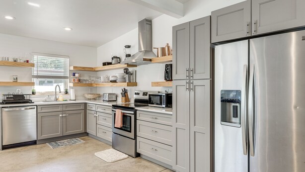 Eine moderne Küche mit Edelstahlgeräten, Holzregalen und einem großen Kühlschrank.
