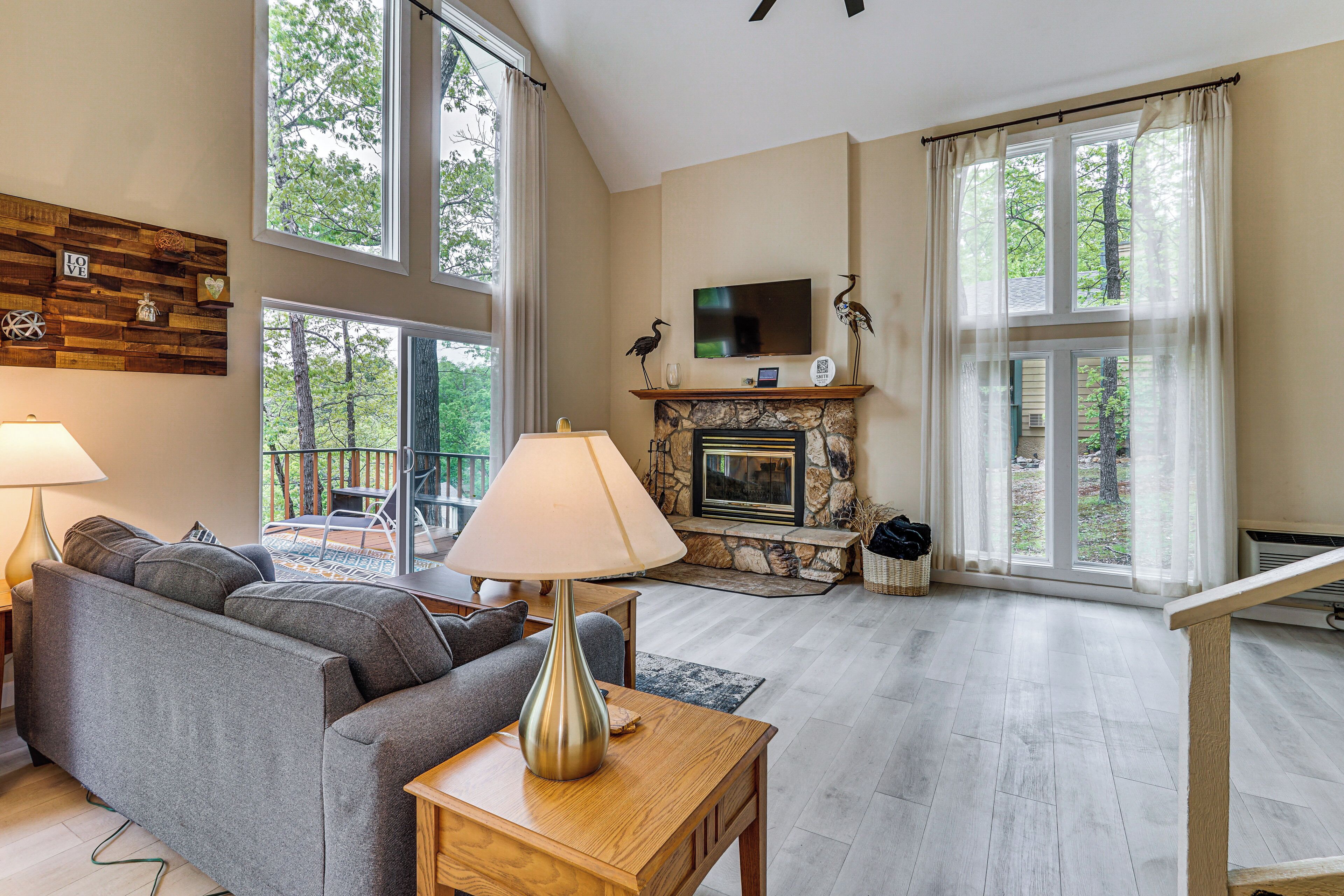 A spacious living room with a fireplace, large windows, a sofa, and a television.