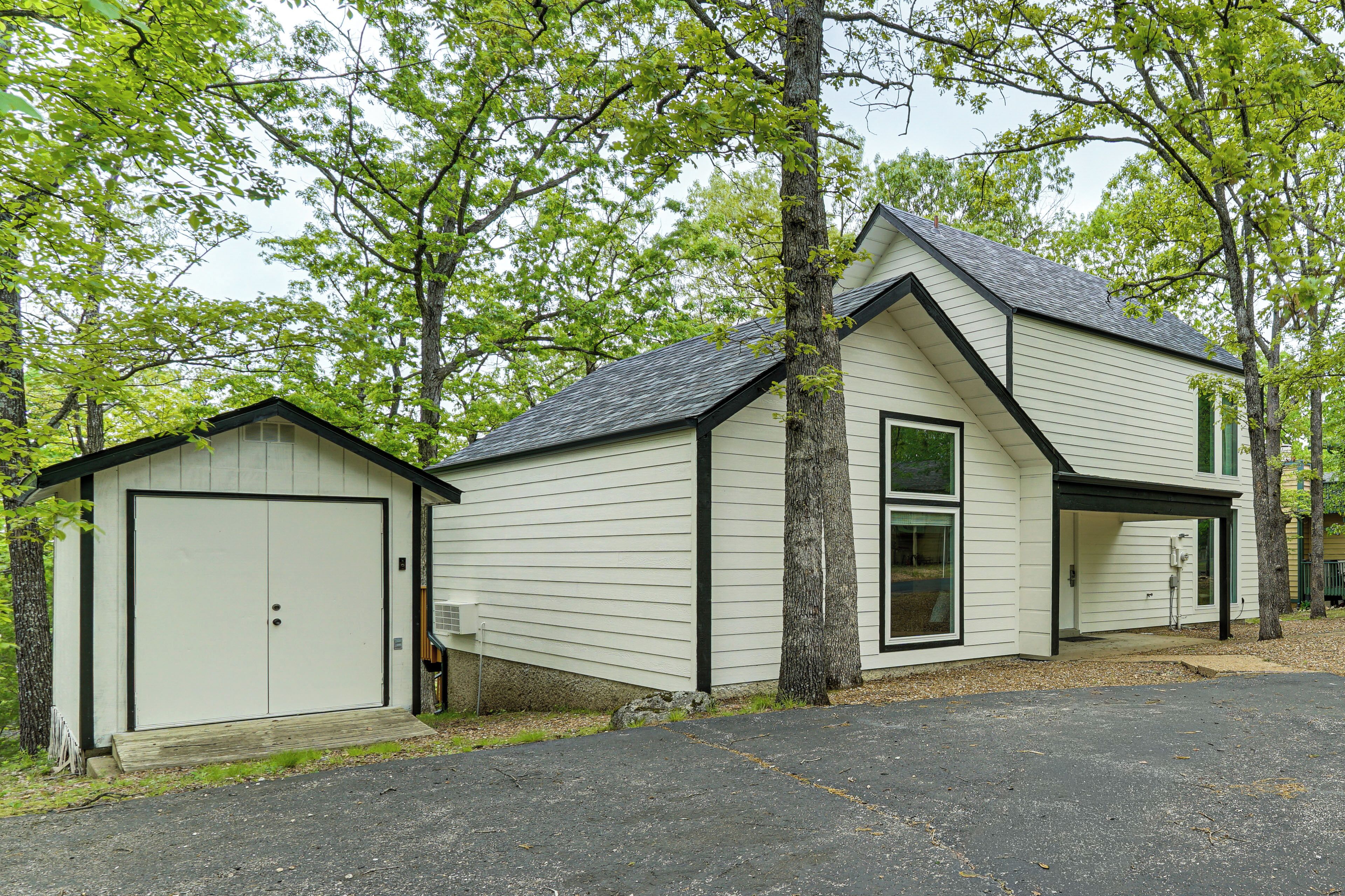 A two-story house with a garage, a covered porch, and a small shed.