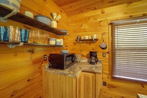 A wooden cabin kitchen with a microwave, coffee maker, and various dishes on shelves. - Butler Cabin w/ Fire Pit: 7 Mi to Doe Mtn! (Mountain City)