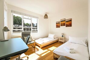 A room with a bed, a desk, a chair, a small table, and a lamp. - British Museum Apartment (Greater London)