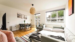 Une chambre moderne comprenant un lit, un canapé, un coin repas et offrant une vue sur les bâtiments grâce à de grandes fenêtres.