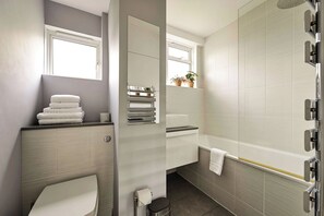 Een moderne badkamer met toilet, wastafel en douche.
