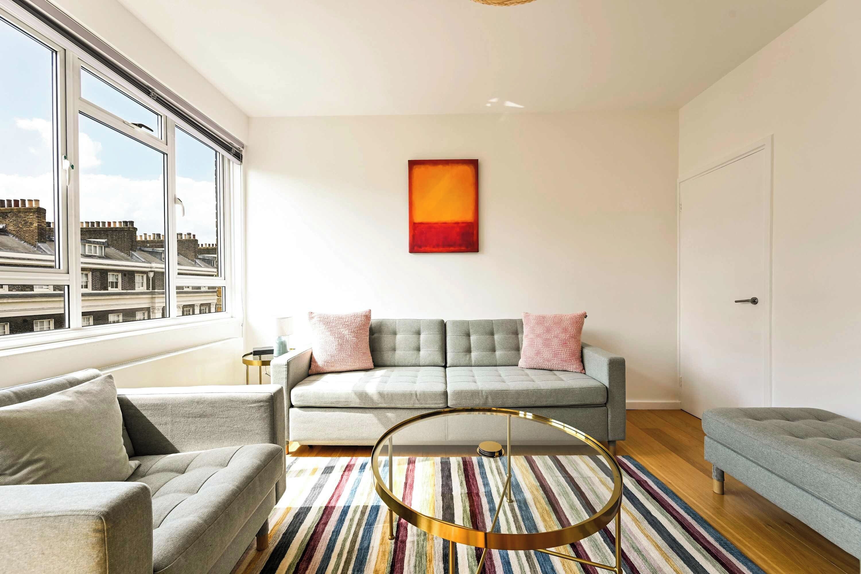 A modern living room with a sofa, a round coffee table, and a colorful striped rug.
