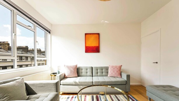 Un salon moderne avec un canapé, une table basse ronde et un tapis rayé aux couleurs vives.
