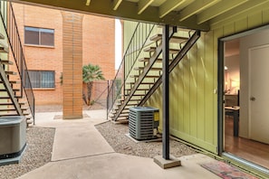 A covered outdoor area with a staircase, a brick building, and an air conditioning unit. - Pool Access! Quiet Condo, 2 Mi to Reid Park (Tucson)
