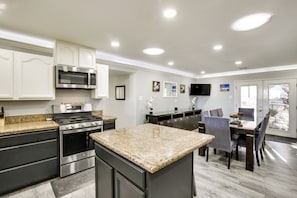 A modern kitchen with stainless steel appliances, granite countertops, and a dining area with a dark wood table and chairs. - Mountain-view Haven: Home Near Fort Bliss (El Paso)