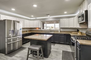 A modern kitchen with stainless steel appliances, granite countertops, and a large island with a bar stool. - Mountain-view Haven: Home Near Fort Bliss (El Paso)