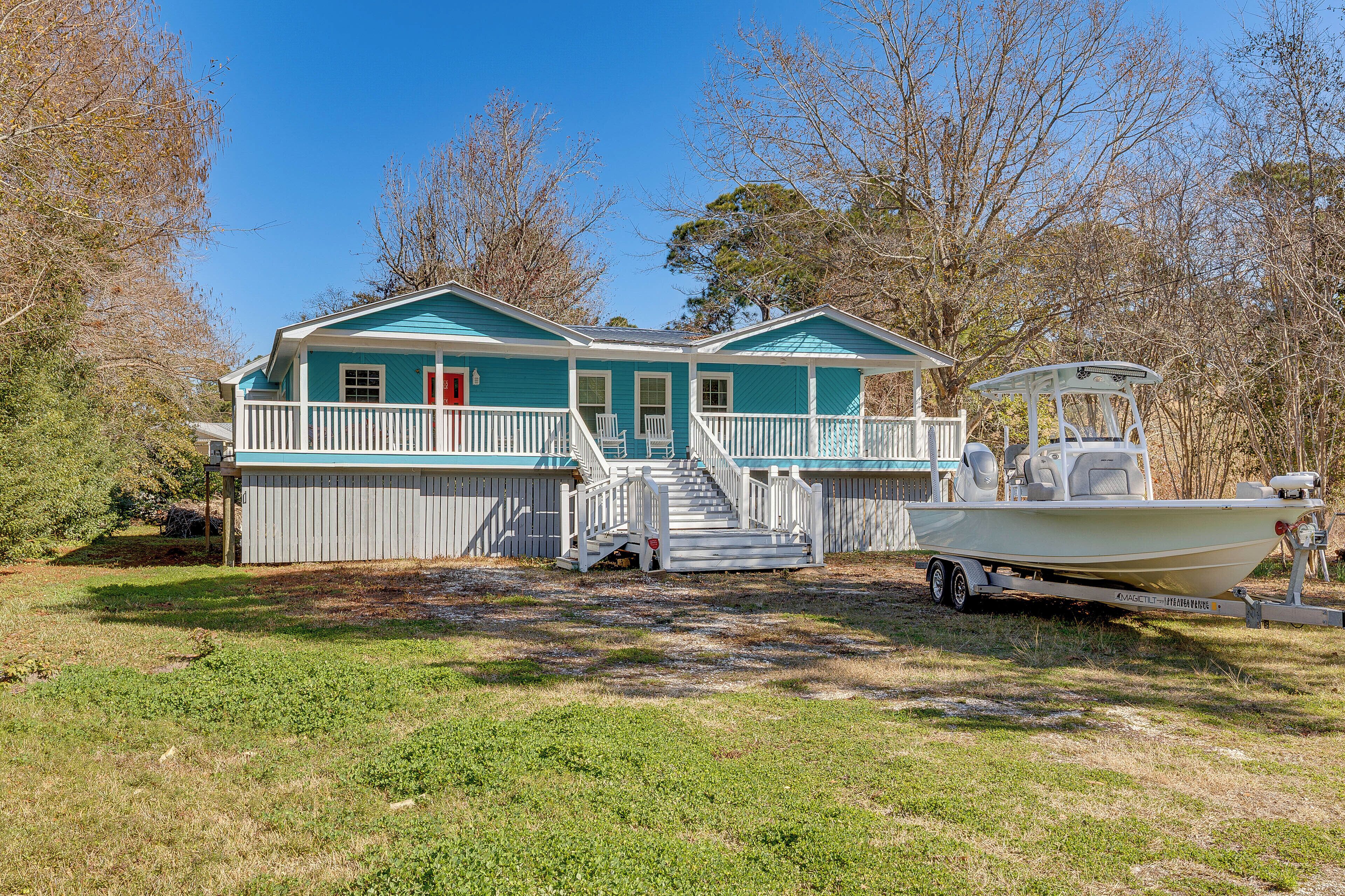 A house with a porch, a boat on a trailer, and a staircase leading to the entrance.