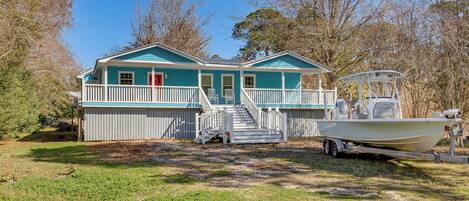 A house with a porch, a boat on a trailer, and a staircase leading to the entrance.