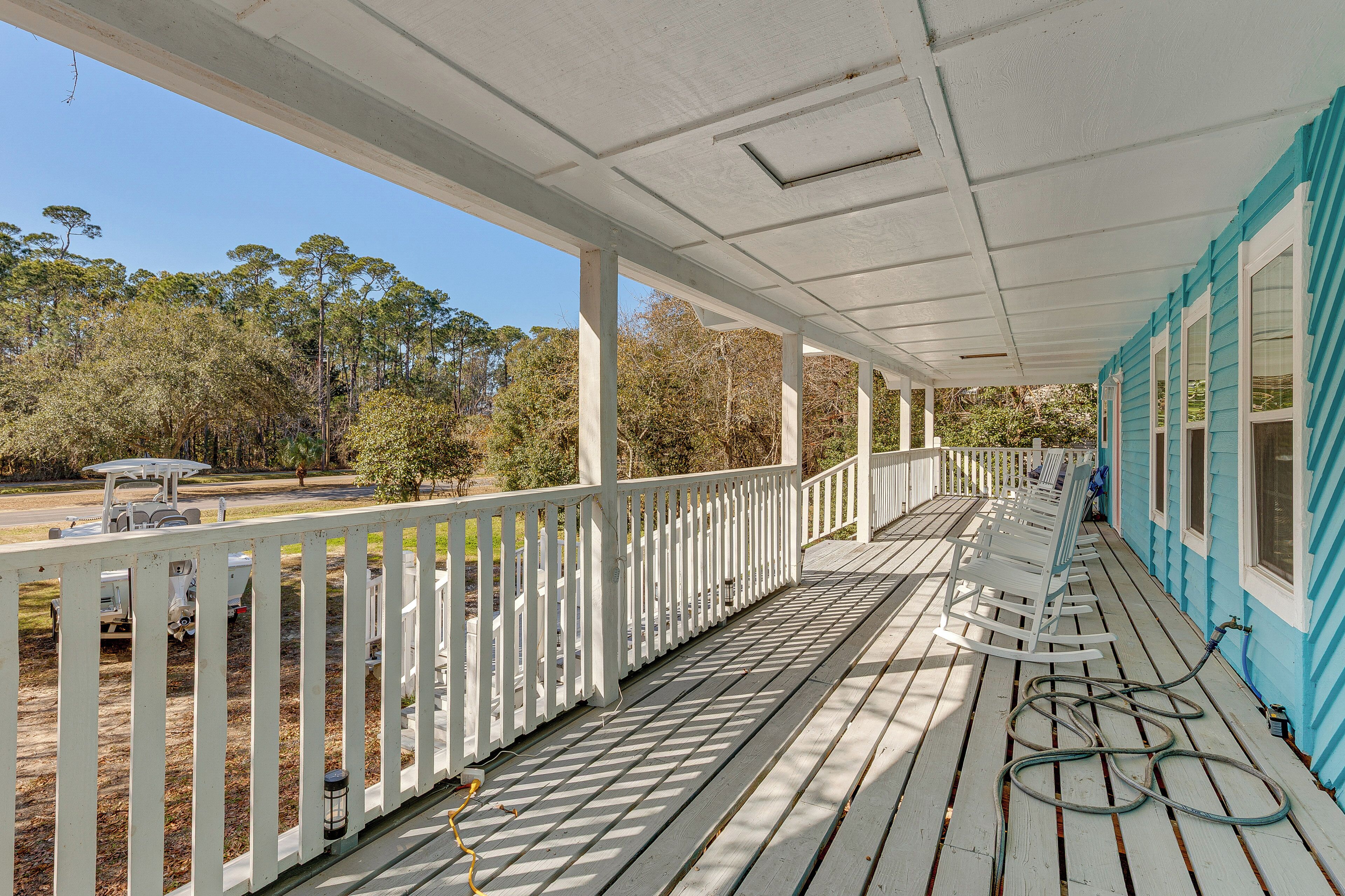 A covered porch with white railings and a blue wall, leading to a house.