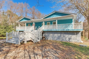 Ein zweistöckiges Haus mit Veranda, Treppe und umzäunter Garten.