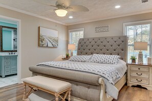Ein Schlafzimmer mit einem großen Bett, einer Bank, einem Nachttisch, einem Deckenventilator und einem Fenster.
