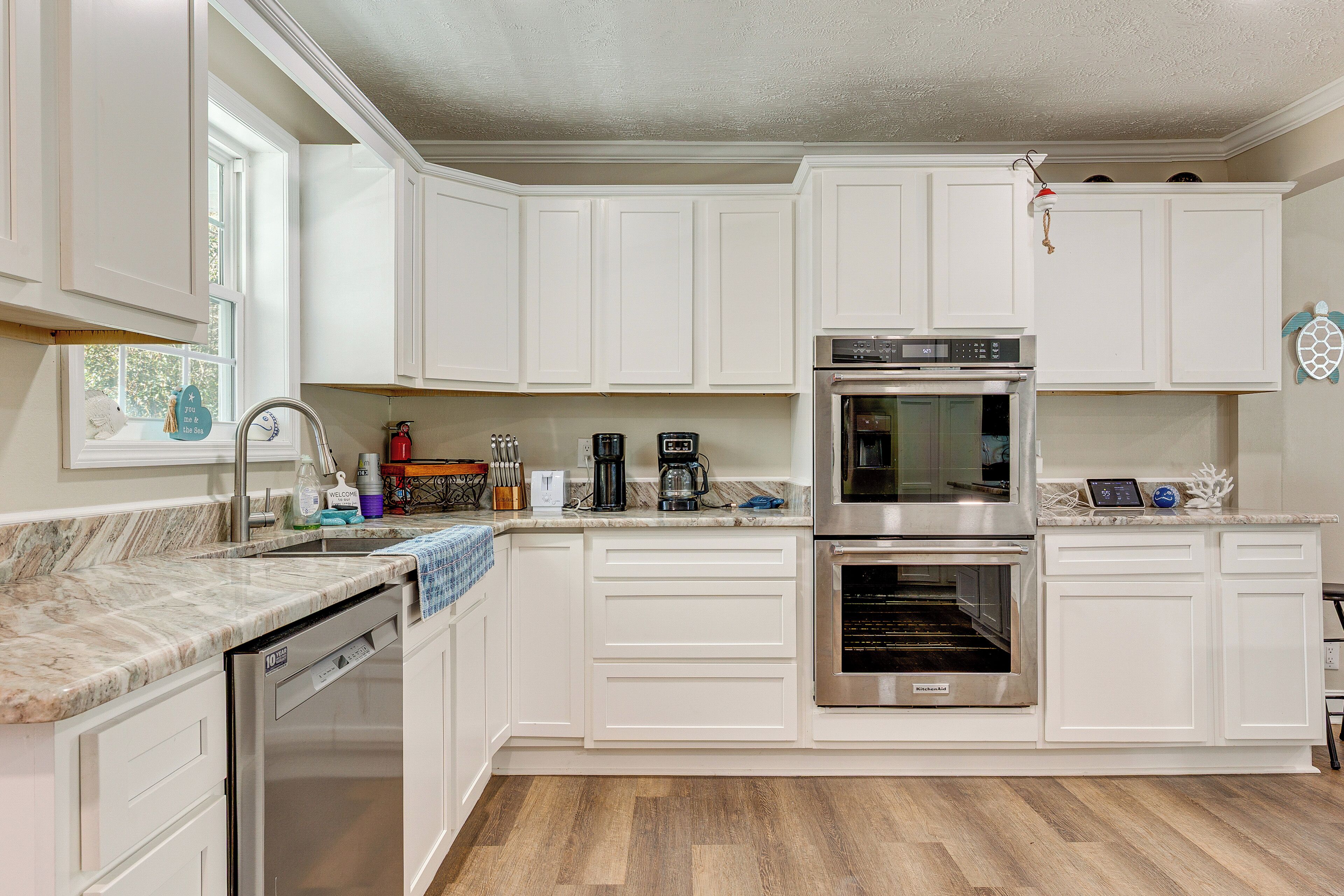 A kitchen with white cabinets, a dishwasher, a coffee maker, and an oven.