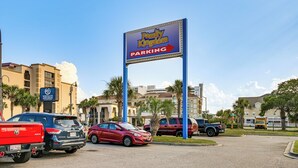 Een parkeersbord voor Family Kingdom, met een goed zicht op de omliggende gebouwen en geparkeerde voertuigen.