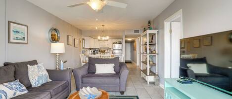 A living room with a sofa, a coffee table, a TV, and a ceiling fan.