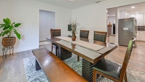 A dining area with a long table, chairs, a bench, a potted plant, and a vase. - 4 Mi to Charlotte Speedway! 3BD Home w/ Deck (Harrisburg)