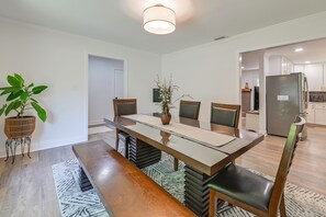 A dining area with a long table, chairs, a bench, a potted plant, and a vase.