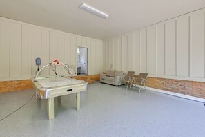 A room with a pool table, a sofa, and a chair.