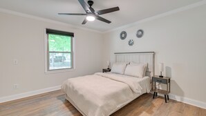 A bedroom with a bed, a nightstand, a ceiling fan, a window, and wall decorations. - 4 Mi to Charlotte Speedway! 3BD Home w/ Deck (Harrisburg)