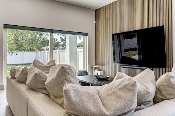 A modern living room with a sofa, television, and a dining table.