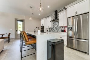 A modern kitchen with white cabinets, a stainless steel refrigerator, a built-in oven, and a coffee maker. - Private Yard & Covered Patio: Modern Tampa Getaway (Tampa)