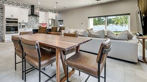 A modern kitchen with white cabinets, a large dining table, and a built-in oven. - Private Yard & Covered Patio: Modern Tampa Getaway (Tampa)
