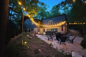 Una casa con patio, mobiliario exterior e iluminación colgante.