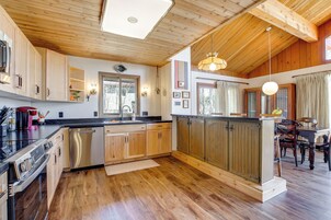 Una cocina moderna con armarios de madera, lavavajillas y un comedor con mesa y sillas.