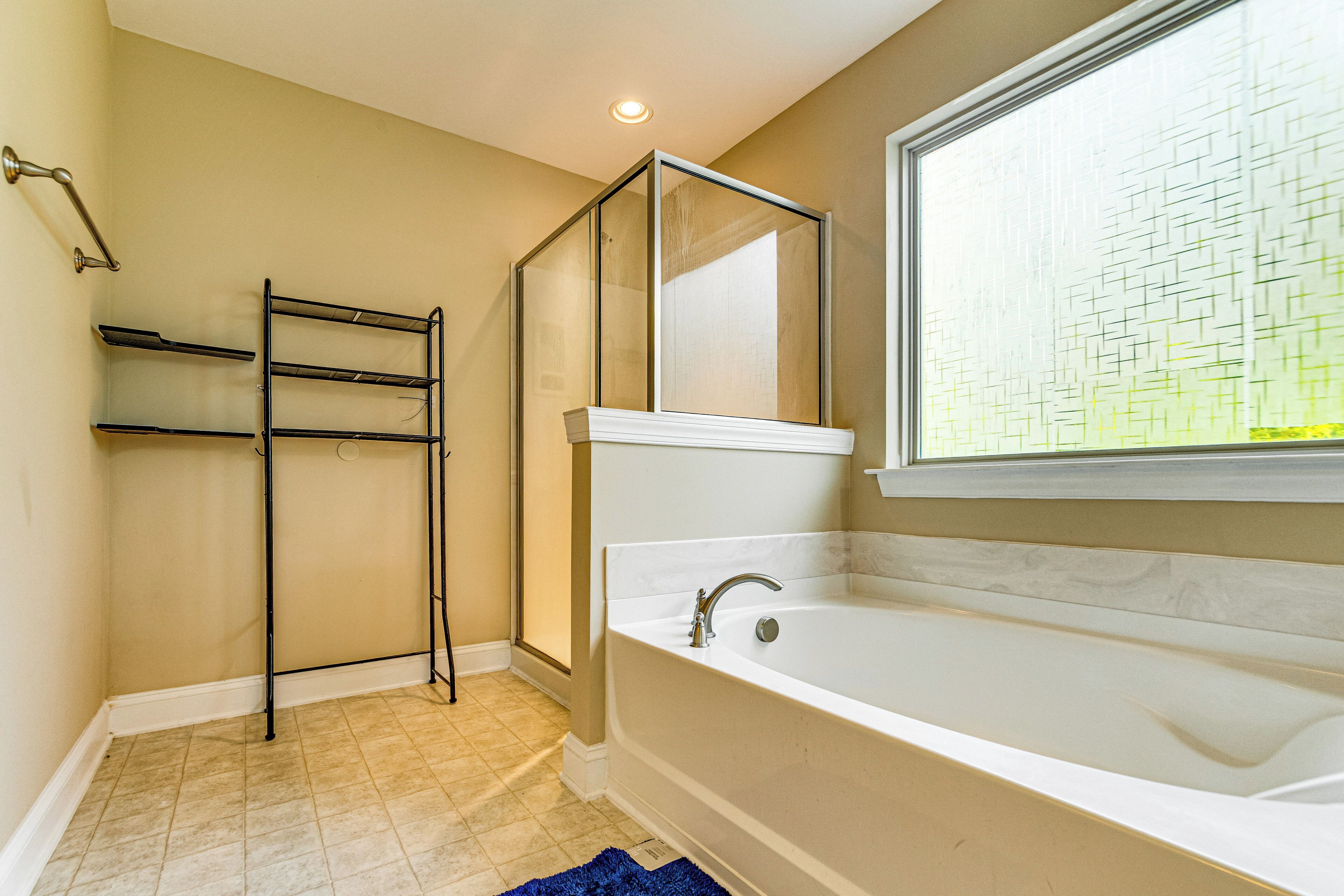 Un baño con bañera, ventana con vistas, toallero y zona de ducha.
