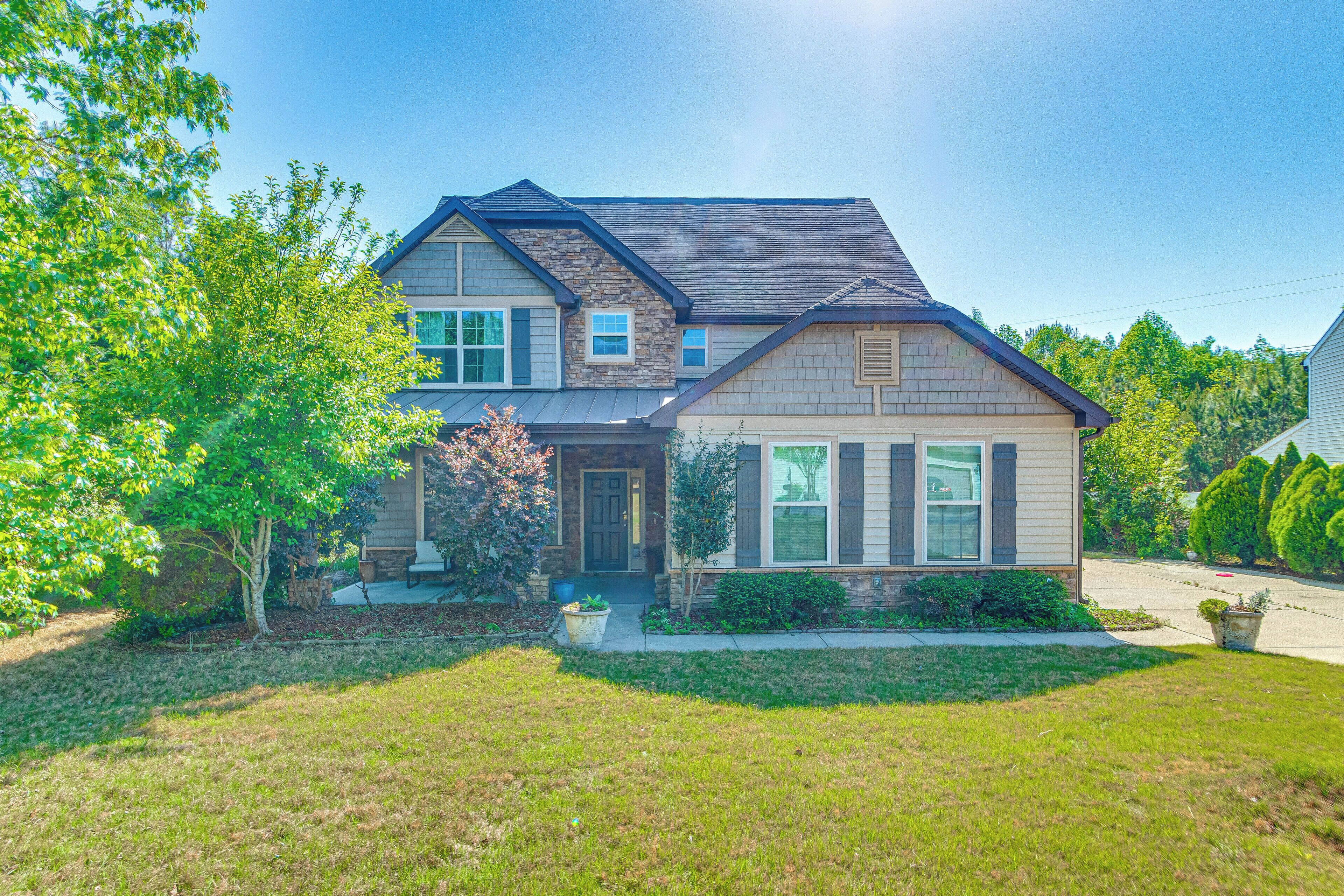 A two-story house with a front porch, a driveway, and a well-maintained lawn.