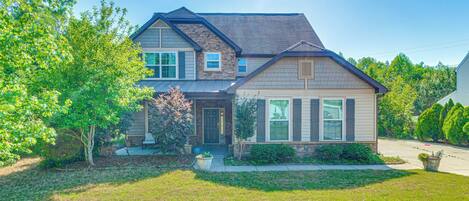 A two-story house with a front porch, a driveway, and a well-maintained lawn.
