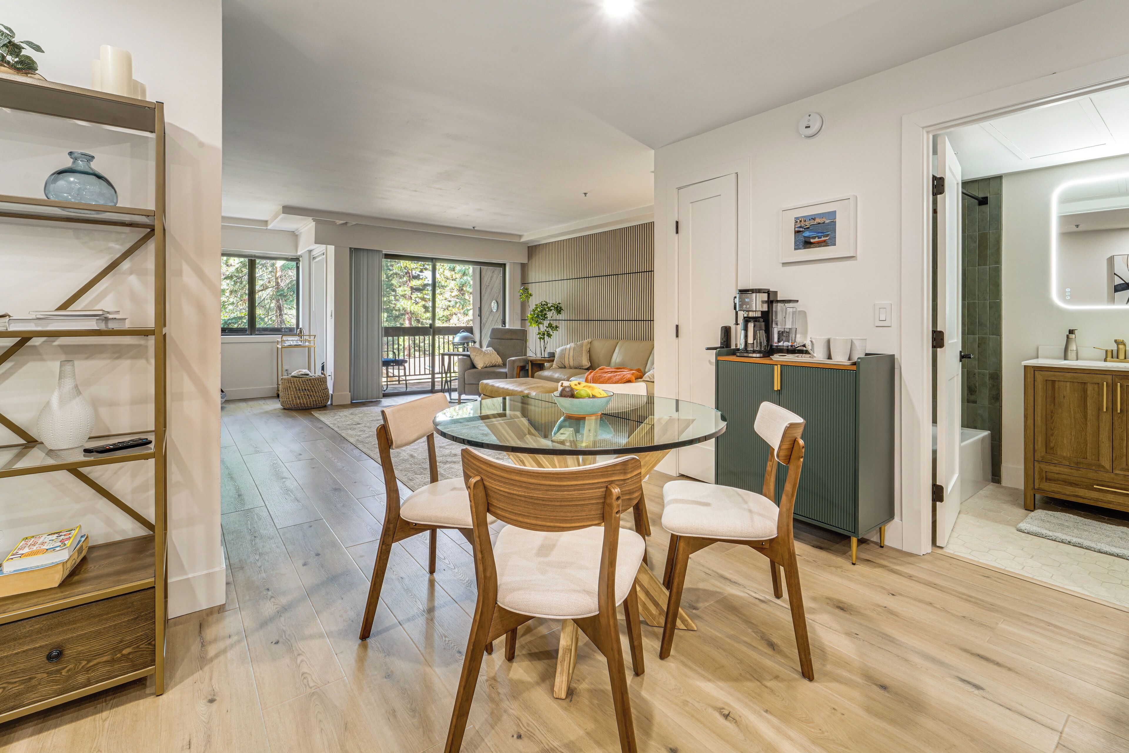 A modern kitchen with a glass dining table, wooden chairs, and a built-in oven.