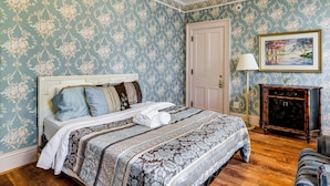 Un dormitorio con una cama, una mesita de noche, una lámpara, un cuadro y una puerta.