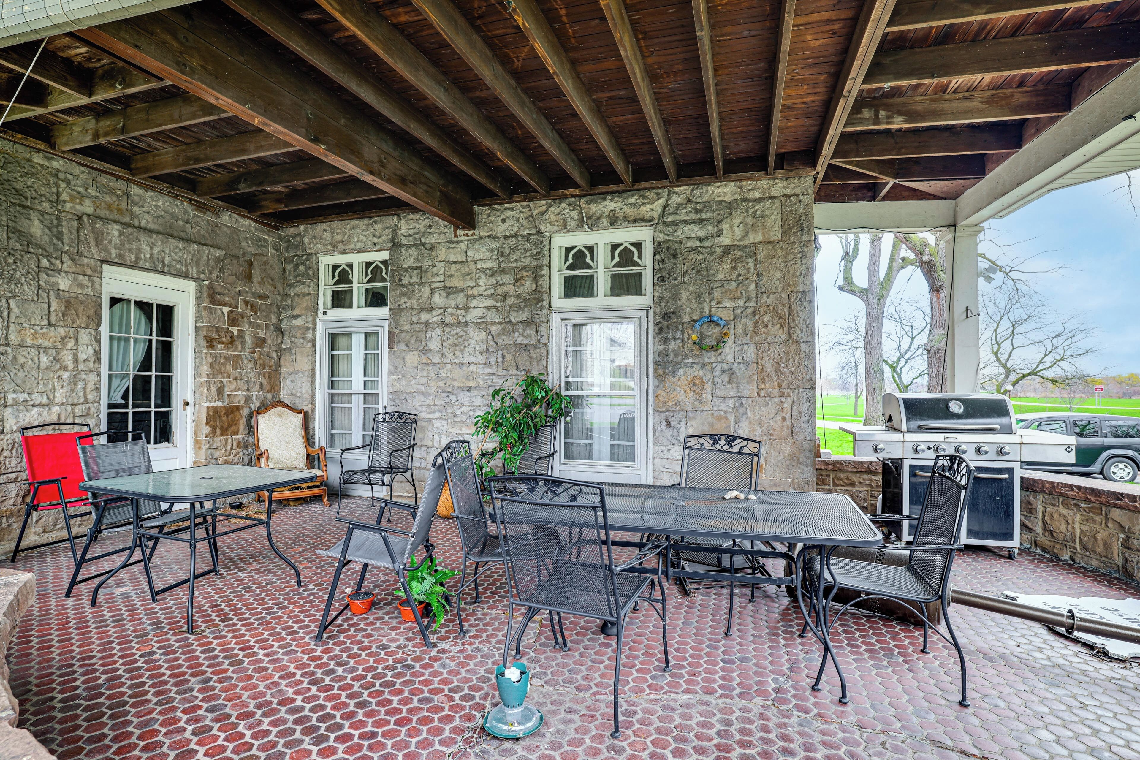 A covered patio with stone walls, a grill, and outdoor seating.