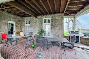 A covered patio with stone walls, a grill, and outdoor seating. - Historic Victorian Cottage, 1 Mi to Niagara Falls (Niagara Falls)
