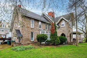 A stone house with a large front yard, a covered porch, and a chimney. - Historic Victorian Cottage, 1 Mi to Niagara Falls (Niagara Falls)