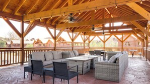 Un patio al aire libre con vigas de madera, mobiliario de mimbre y suelo de piedra.