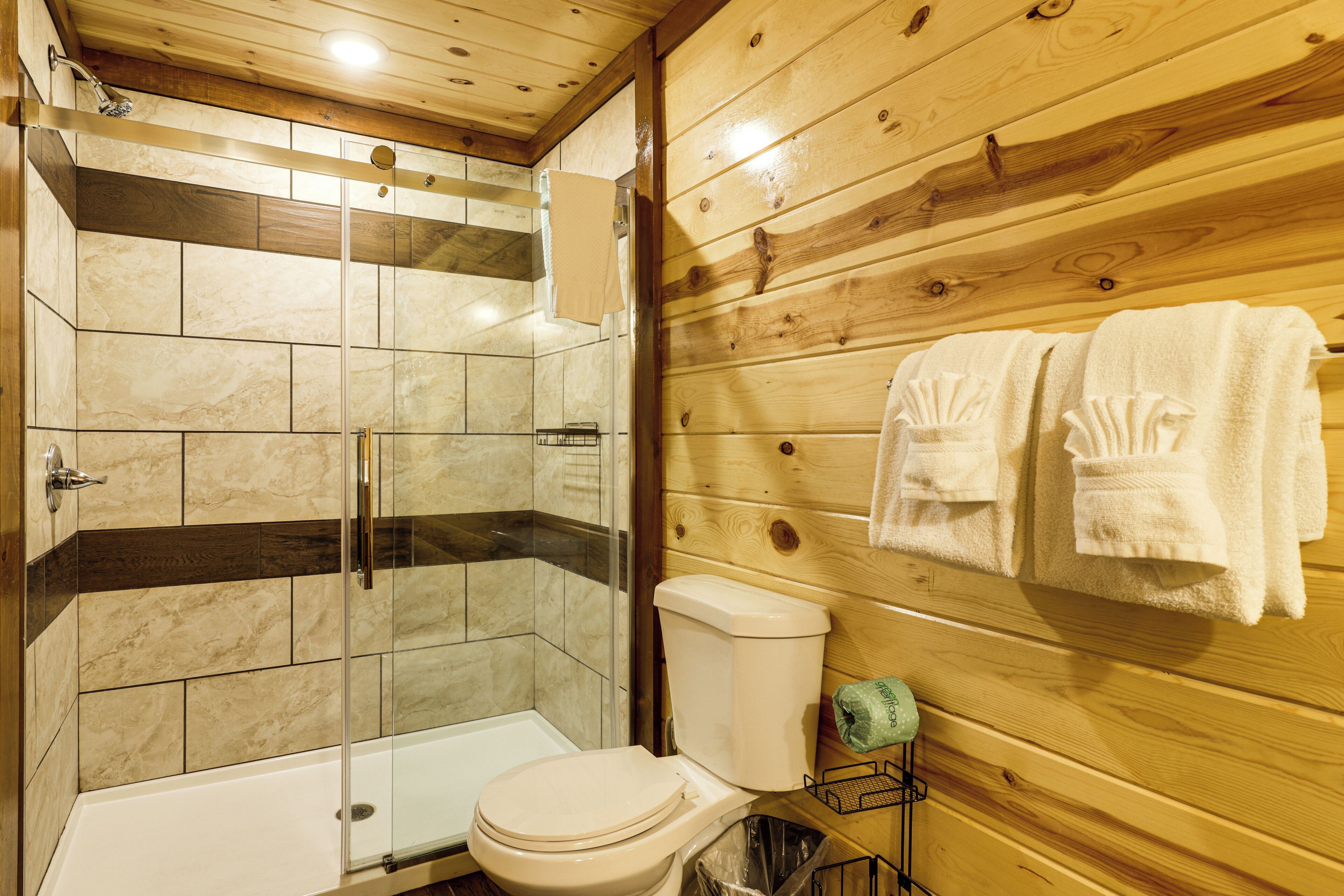 Een badkamer met een douche, toilet en handdoekrek.