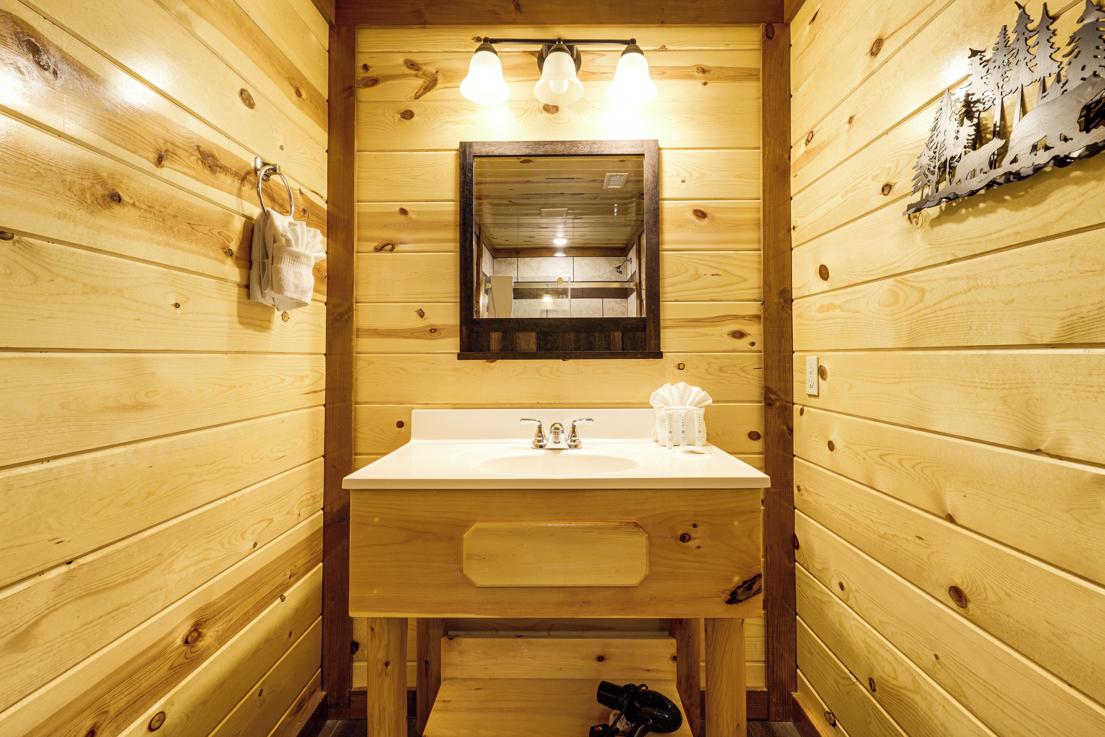 A wooden cabin bathroom with a sink, mirror, and towel rack.