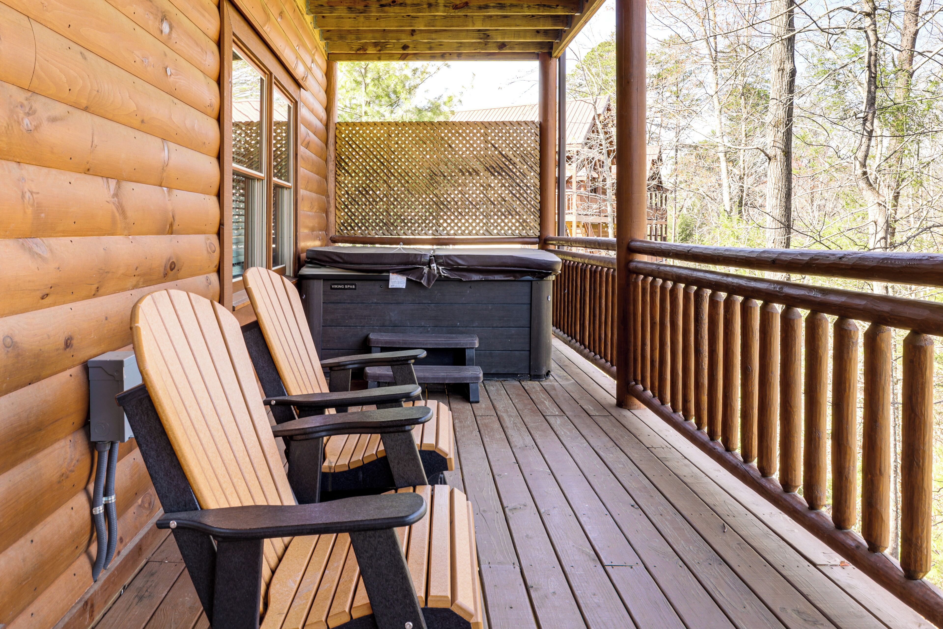 A wooden deck with Adirondack chairs and a hot tub.