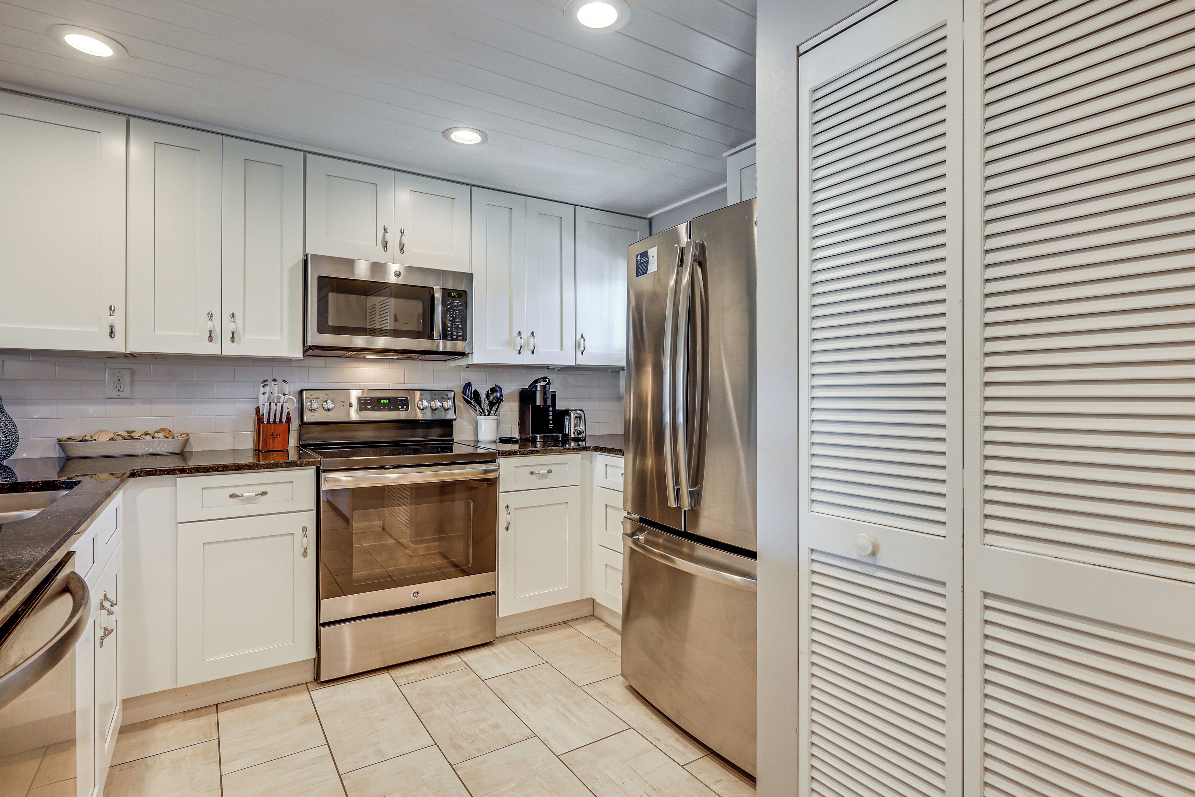 A kitchen with white cabinets, stainless steel appliances, and a tiled floor.