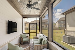 A sunroom with a ceiling fan, a flat-screen TV, and a view of a residential area. - 2 Mi to Dtwn! Newly Built Oxford Retreat w/ Porch (Oxford)