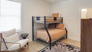 A bunk bed room with a ceiling fan, a small round table, and a chair.