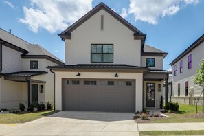 A two-story residential building with a garage, a front porch, and a small front yard with landscaping. - The 5th Quarter: Ole Miss Reunions 2 Mi Away (Oxford)
