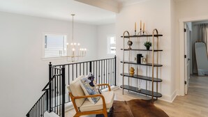A staircase with a black railing, a beige chair with a cushion, and a brown rug.