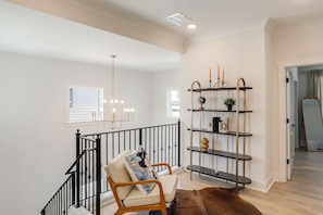 A staircase with a black railing, a beige chair with a cushion, and a brown rug.